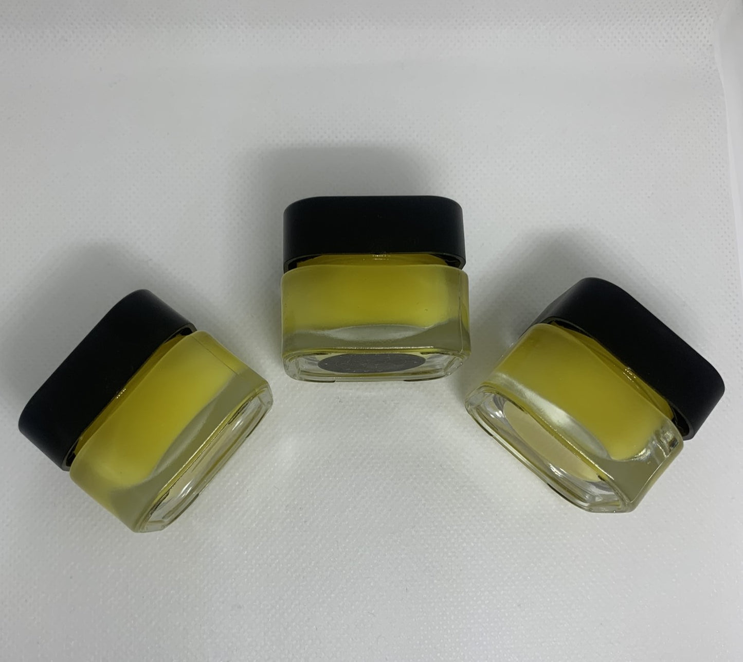 Image of Lucky's Ivy Golden Night Under-Eye Balm. Three closed jars showing the outside of the product, one product having the logo visible.