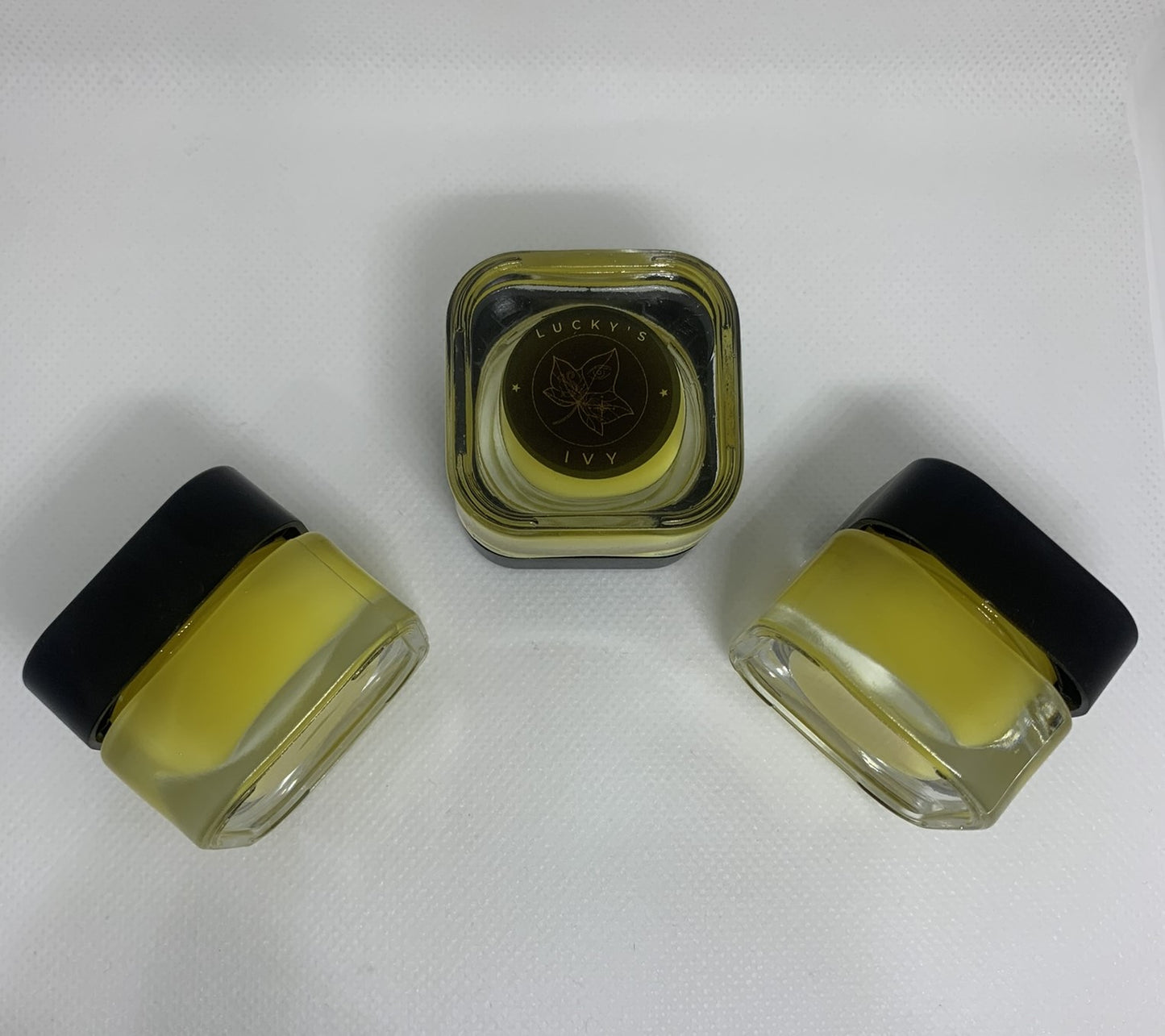 Image of Lucky's Ivy Golden Night Under-Eye Balm. Closed jars showing the outside of the product, one product having the logo visible.